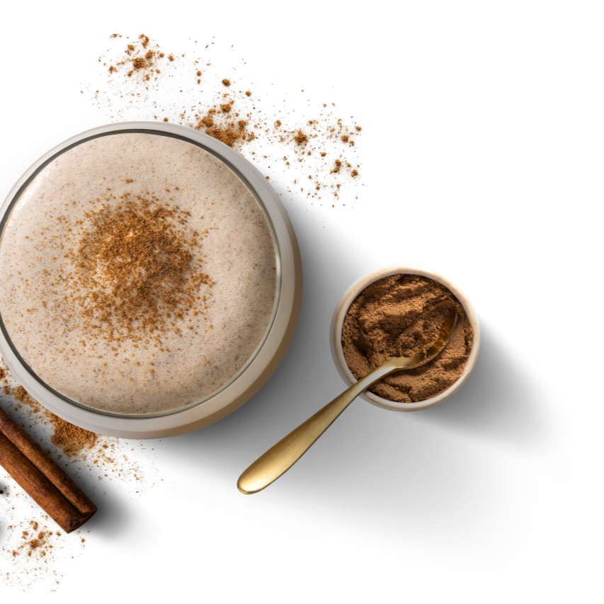 Bovenaanzicht van een Pumpkin Spice Latte met kaneel en een lepeltje ernaast